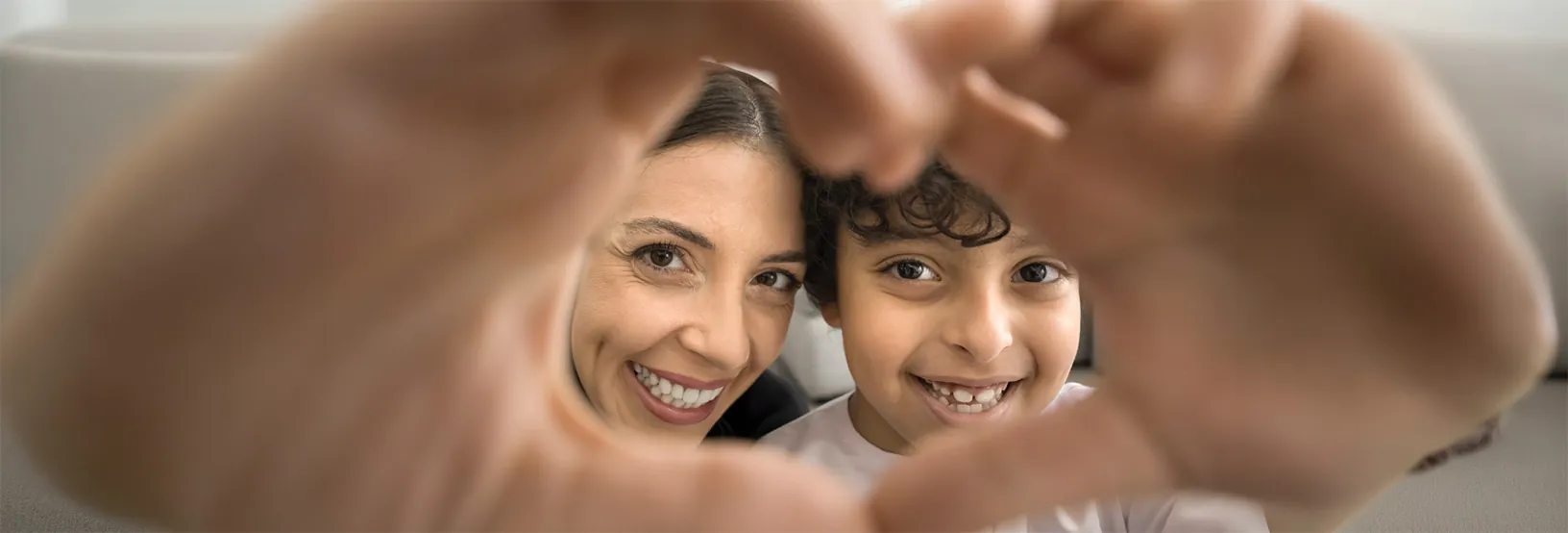 Mother and son smiling, making a heart shape with their hands